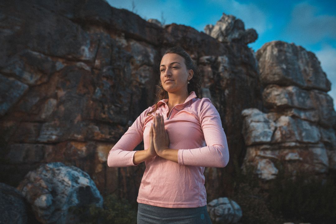 Caucasian woman with joined hands meditating while standing in the mountains - Free Images, Stock Photos and Pictures on Pikwizard.com