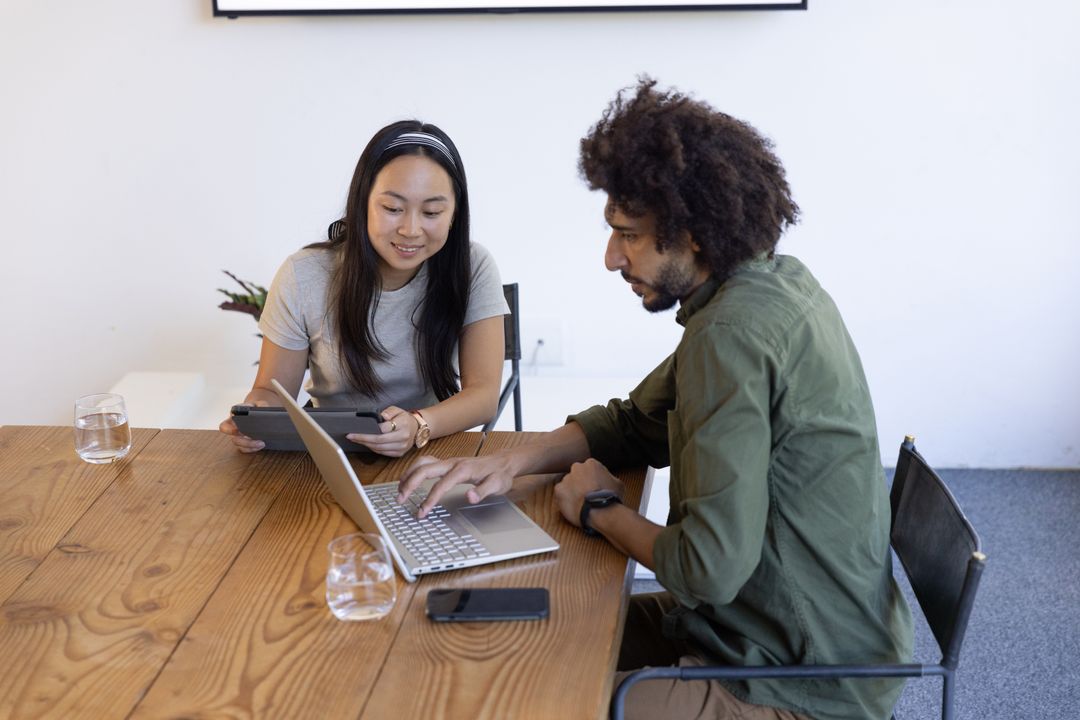 Coworkers Using Laptop and Tablet in Modern Office Workspace