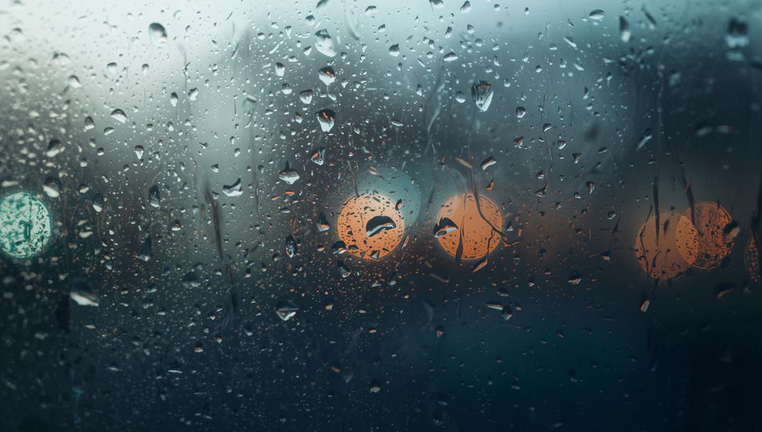 Raindrops Sliding Down Car Window with Teal and Orange Bokeh Lights at Dusk
