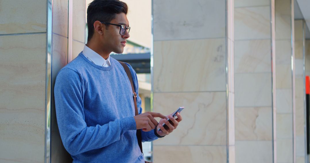 Young Man in Blue Sweater Using Smartphone Outside Office Building - Free Images, Stock Photos and Pictures on Pikwizard.com