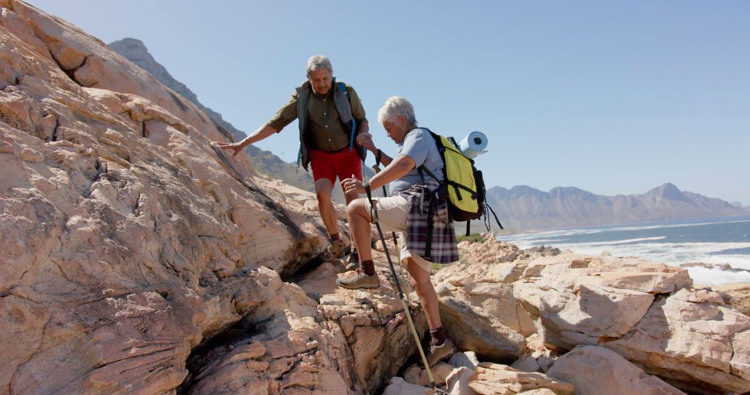 Senior Couple Hiking in Rugged Mountain Terrain by Ocean - Free Images, Stock Photos and Pictures on Pikwizard.com