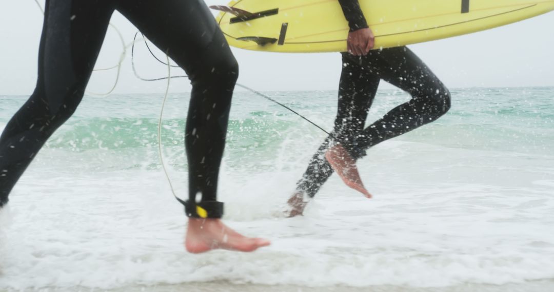 Surfers Running with Surfboards Along the Sandy Beach