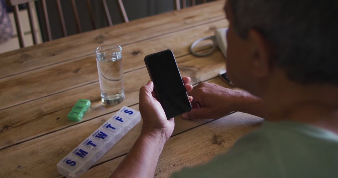 Senior Checking Smartphone at Table with Pill Organizer - Free Images, Stock Photos and Pictures on Pikwizard.com