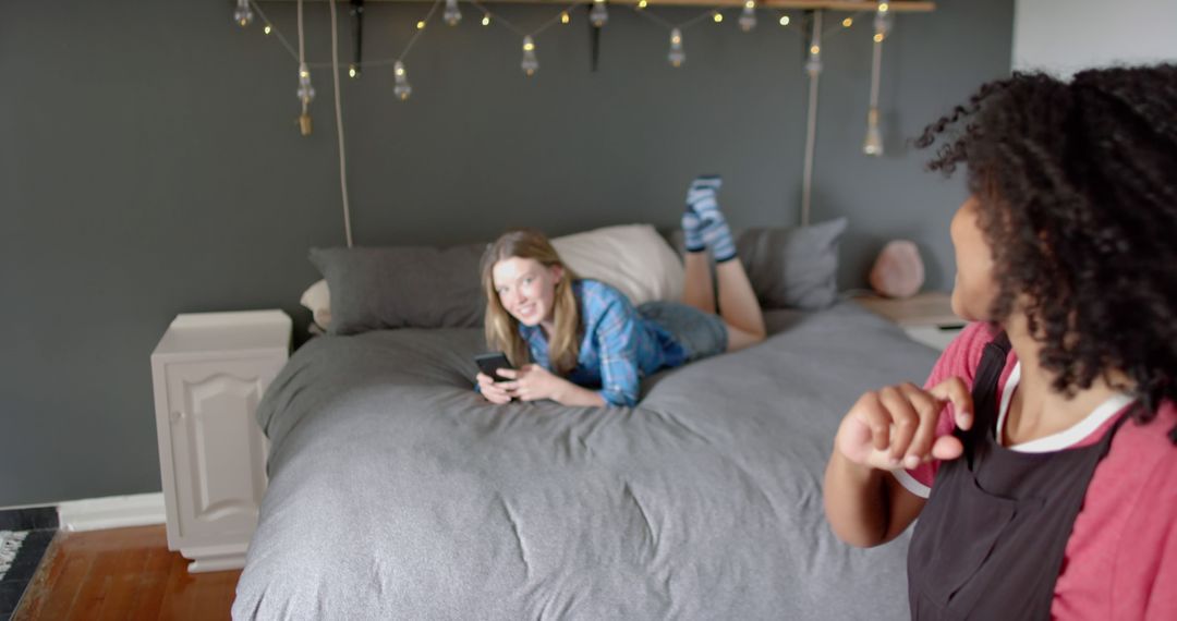 Friends Relaxing on a Bed with Smartphone in Cozy Bedroom - Free Images, Stock Photos and Pictures on Pikwizard.com