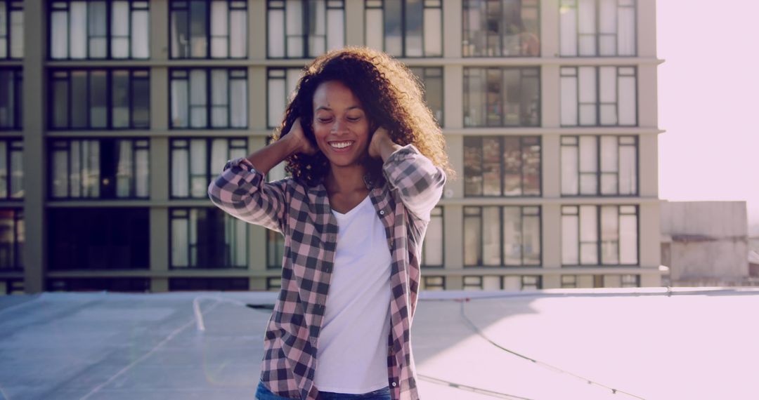 Young woman enjoying rooftop sunshine in casual attire - Free Images, Stock Photos and Pictures on Pikwizard.com