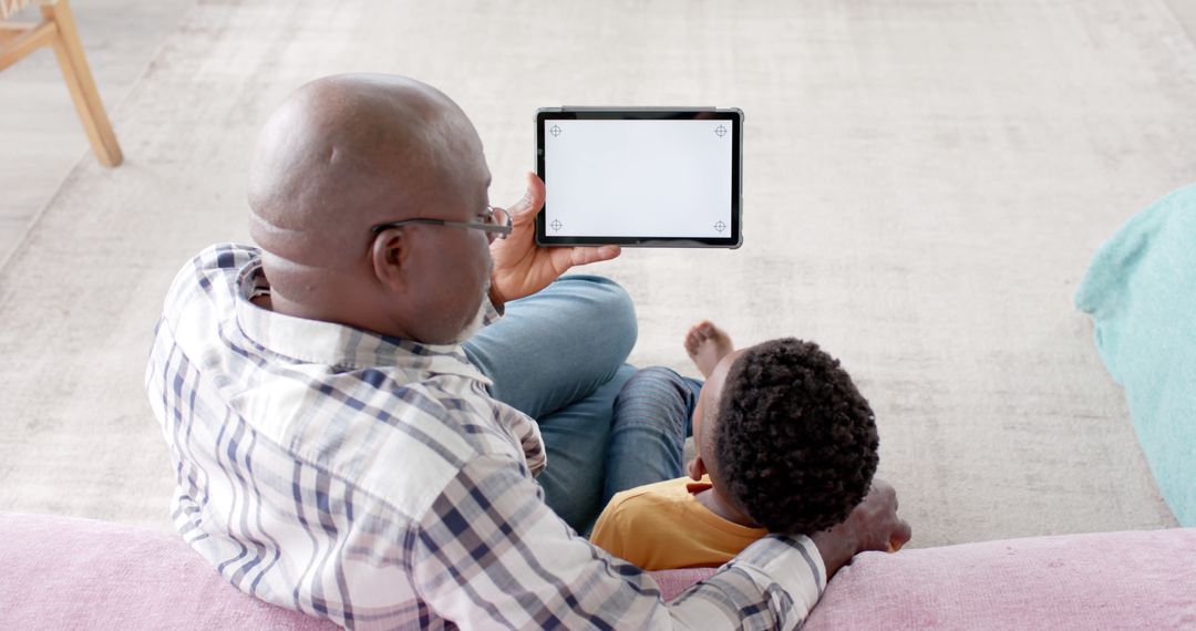 Father Showing Digital Tablet to Child in Cozy Living Room - Free Images, Stock Photos and Pictures on Pikwizard.com