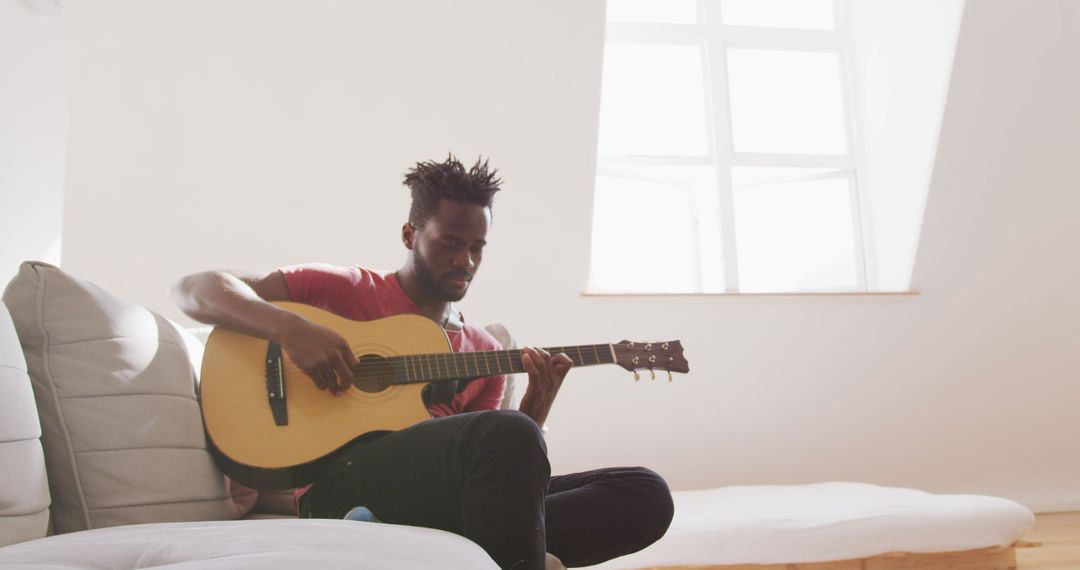 Man Relaxing Playing Guitar by Window in Bright Room