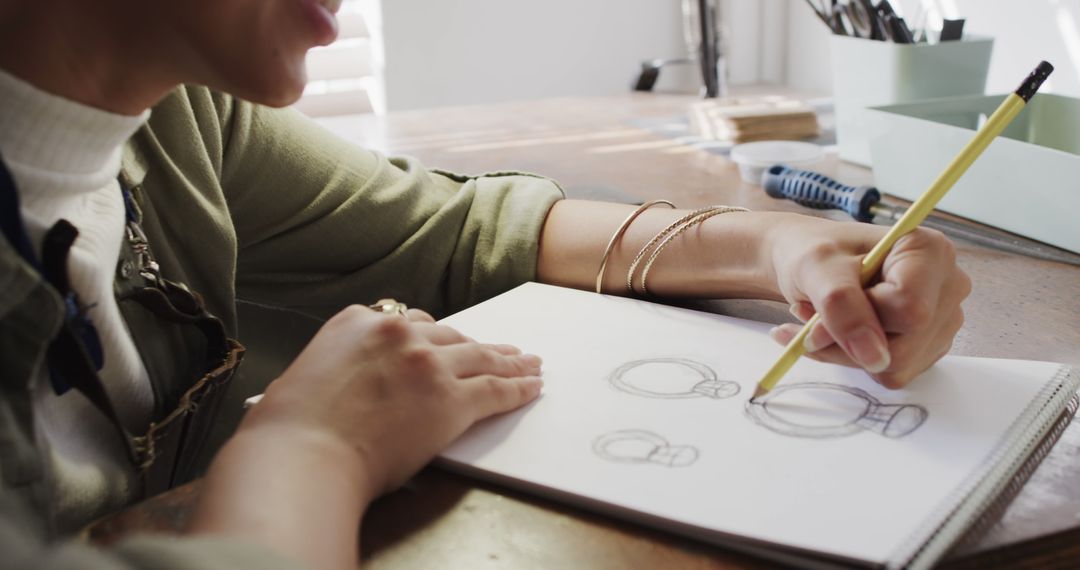 Close-Up of Woman Sketching Designs in Notebook at Workspace - Free Images, Stock Photos and Pictures on Pikwizard.com