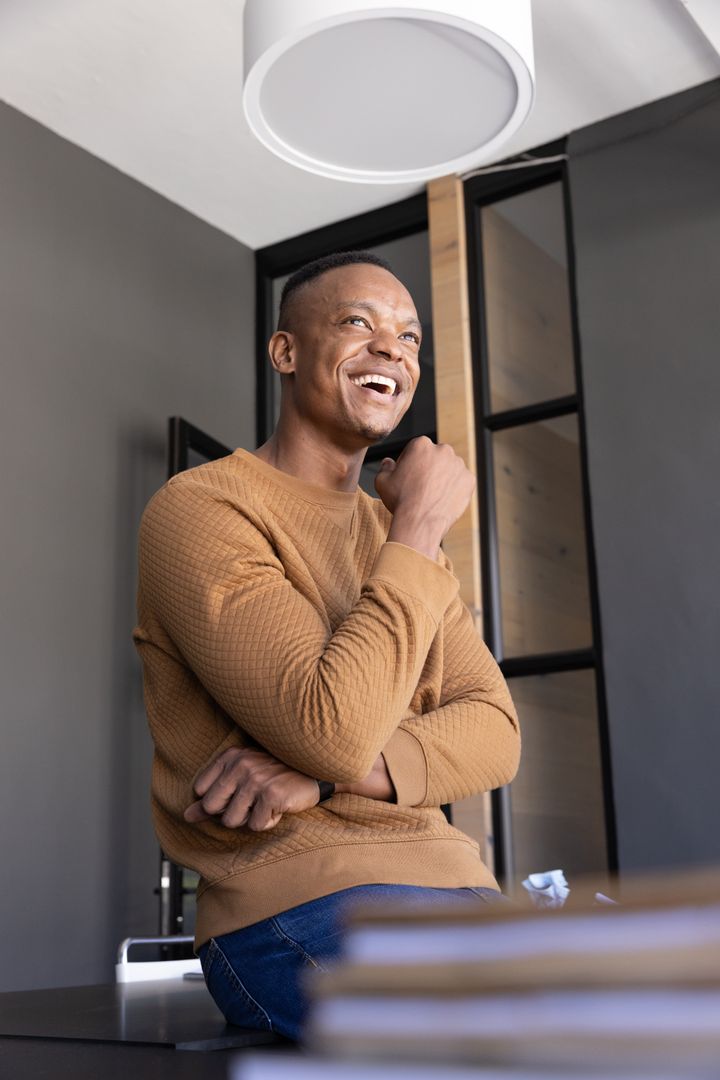 African American Professional Smiling and Contemplating while Sitting in Modern Office