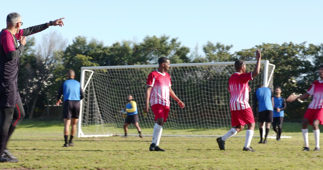 Senior Coach Instructing Soccer Team on Outdoor Field