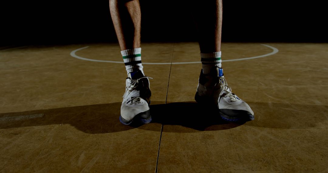 Basketball Player Stands Ready on Court Focusing on Athletic Shoes