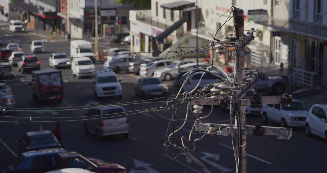 Tangled utility pole carrying power lines above busy downtown intersection and traffic