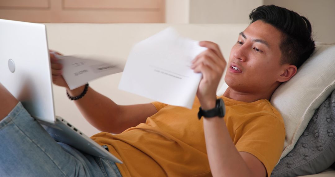Young Man Reviewing Documents While Working Leisurely at Home