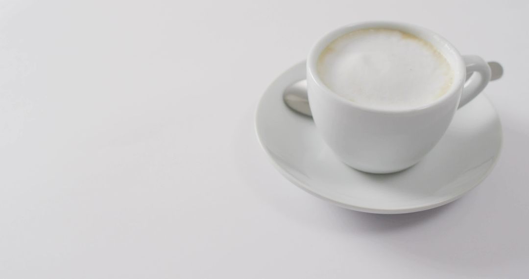 Minimalist White Cappuccino Cup Sitting on Saucer with Spoon and Copy Space for Branding