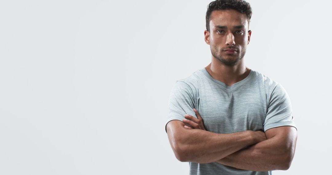 Confident Athletic Man Standing with Crossed Arms in Studio