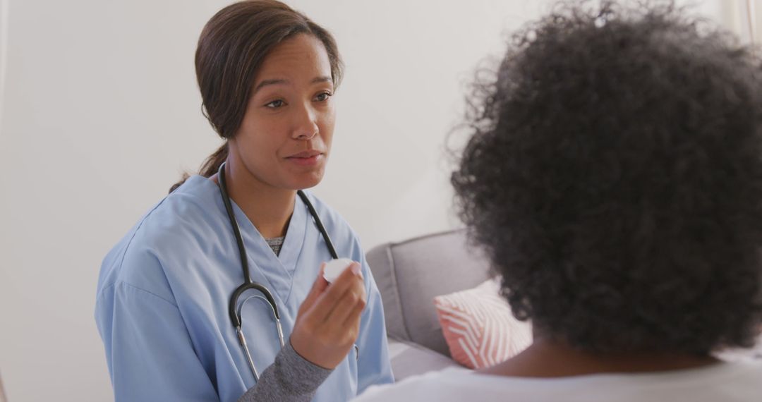 Senior african american woman and female doctor sitting on bed, holding medicines and talking - Free Images, Stock Photos and Pictures on Pikwizard.com