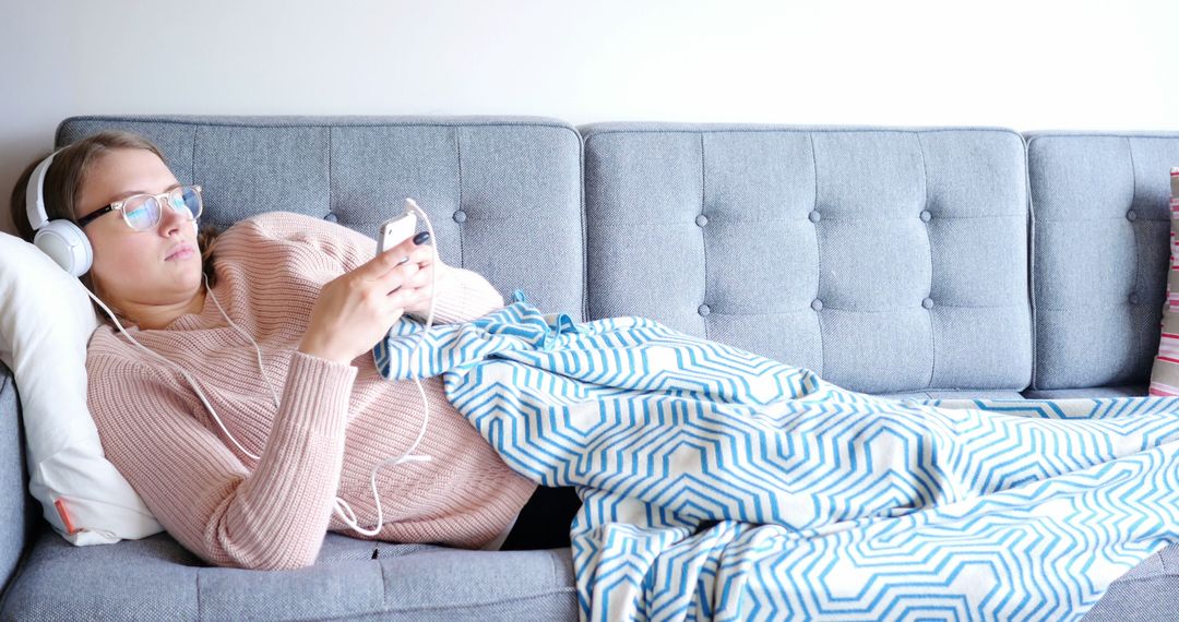 Woman Relaxing on Couch Listening to Music with Headphones and Smartphone - Free Images, Stock Photos and Pictures on Pikwizard.com