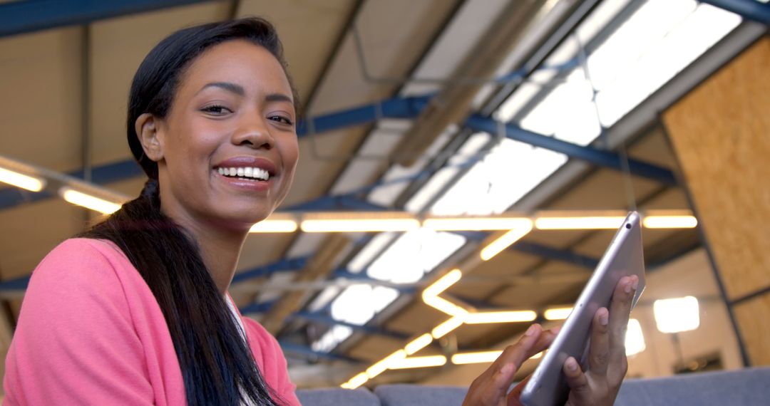 Smiling Woman Using Tablet in Modern Industrial Space - Free Images, Stock Photos and Pictures on Pikwizard.com