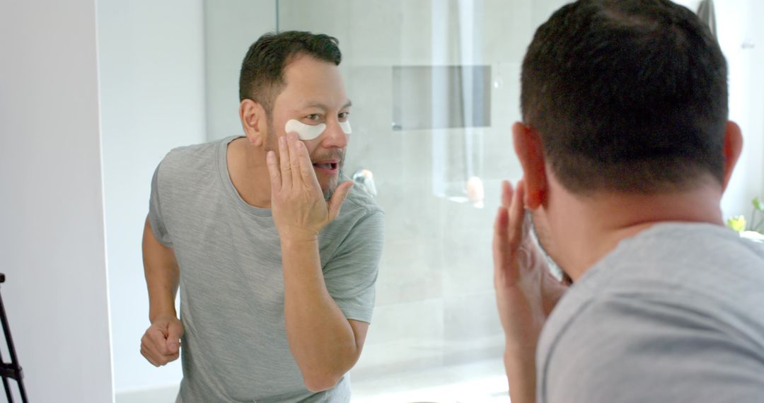 Asian Man Applying Skincare Patch in Bathroom Mirror
