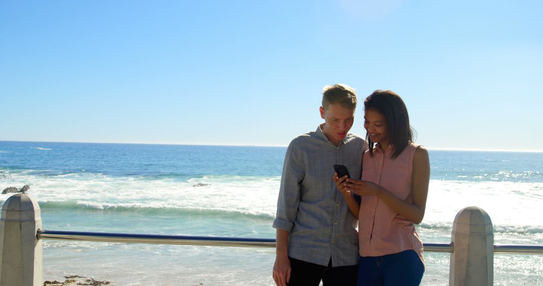 Couple Enjoying Beachfront Scenery and Sharing Moments on Smartphone - Free Images, Stock Photos and Pictures on Pikwizard.com