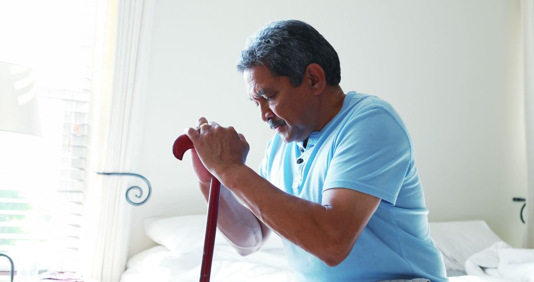 Elderly Man Holding Cane Sitting on Bed in Bright Room - Free Images, Stock Photos and Pictures on Pikwizard.com