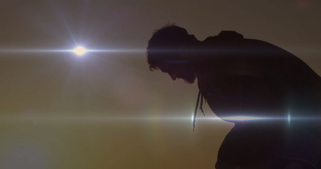 Silhouette of a Contemplative Man in Hoodie at Sunset