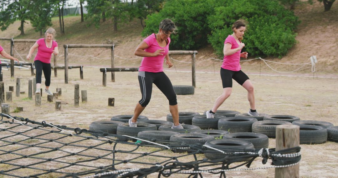 Determined caucasian female friends in pink t shirts crossing logs and tyres at bootcamp training - Free Images, Stock Photos and Pictures on Pikwizard.com