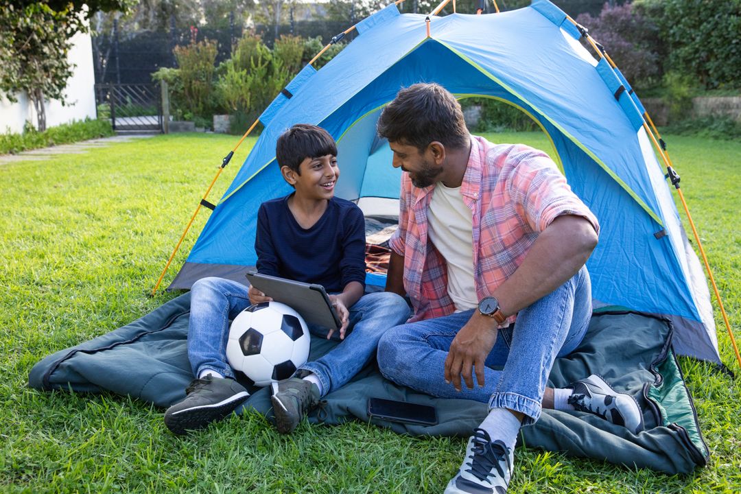 Father and Son Enjoying Camping with Tablet Outside Tent
