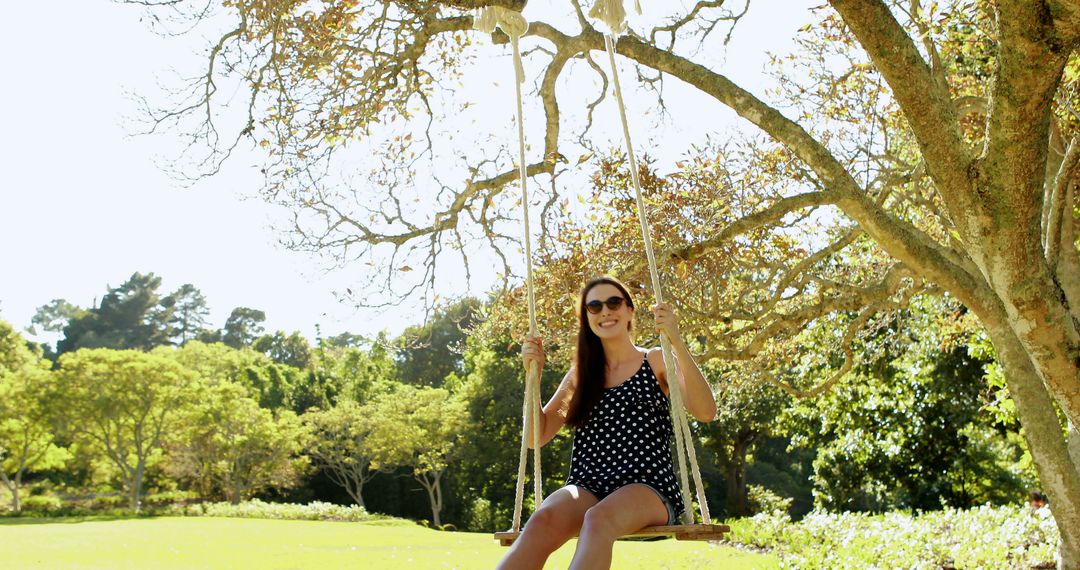 Young woman swinging on swing in park on a sunny day - Free Images, Stock Photos and Pictures on Pikwizard.com