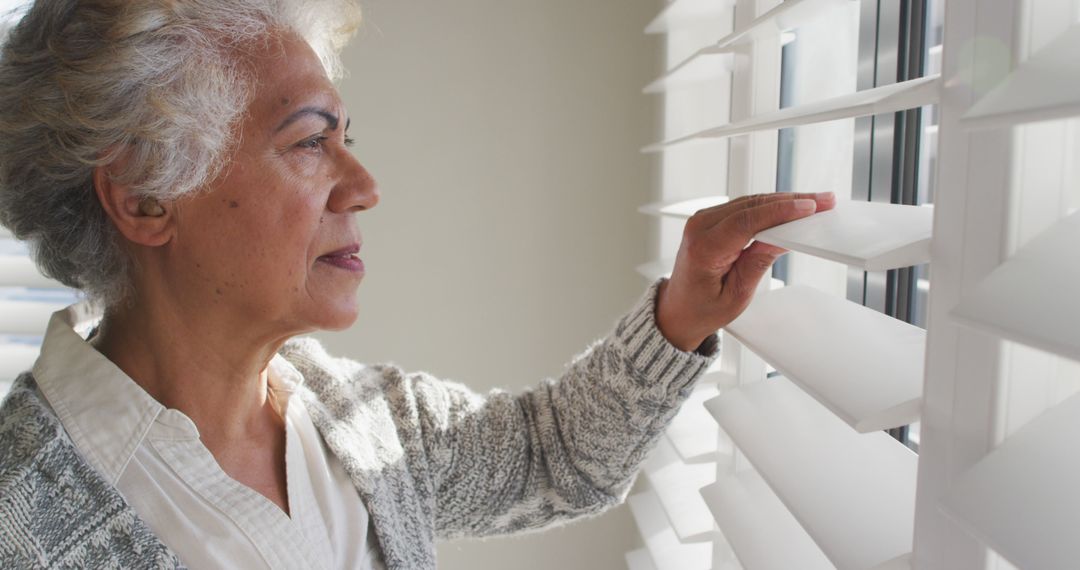 African american senior woman looking out of the window at home - Free Images, Stock Photos and Pictures on Pikwizard.com