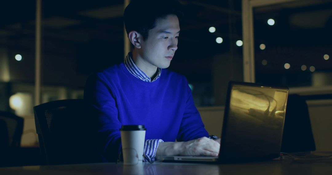 Focused Man Working Late Night in Office Using Laptop