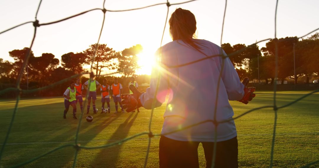 Female goalkeeper preparing for an incoming shot during sunset soccer practice - Free Images, Stock Photos and Pictures on Pikwizard.com