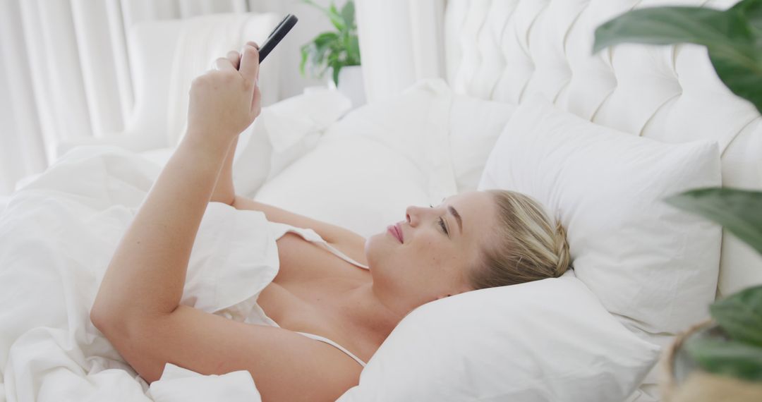 Woman Relaxing in Bed Using Smartphone with White Linens - Free Images, Stock Photos and Pictures on Pikwizard.com