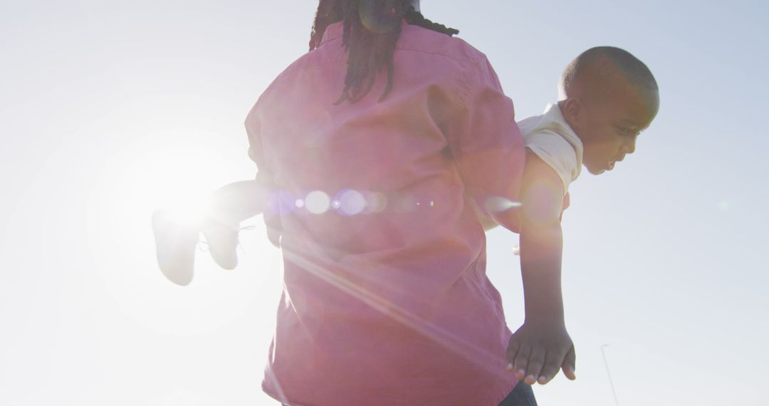 Silhouetted Parent Carrying Child with Sunburst in Background - Free Images, Stock Photos and Pictures on Pikwizard.com