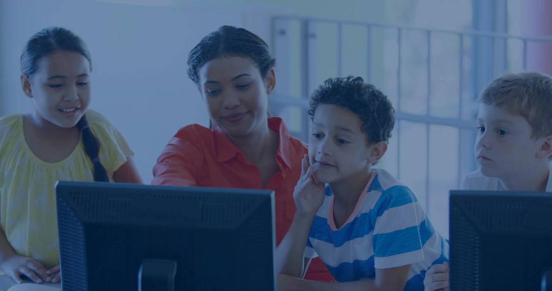 Female Instructor Guiding Schoolchildren Using Desktop Computers in Collaborative Classroom