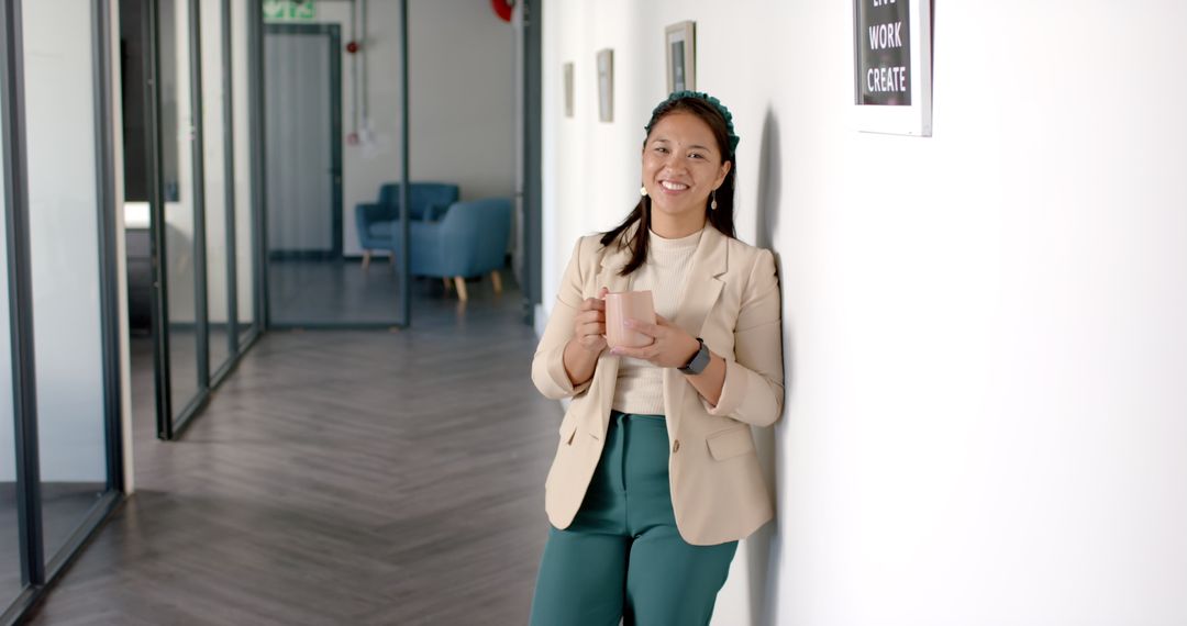 Smiling Professional Enjoys Coffee Break in Modern Office Hallway