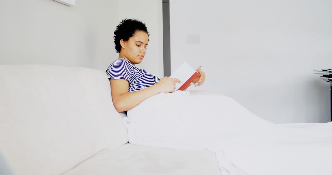 Woman Relaxing on Sofa Reading Book in Modern Living Room - Free Images, Stock Photos and Pictures on Pikwizard.com