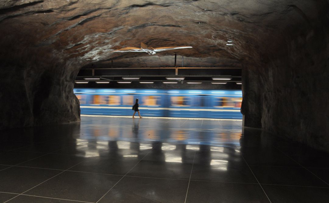 Person Walking Inside Rock-formed Subway Station with Passing Train - Free Images, Stock Photos and Pictures on Pikwizard.com