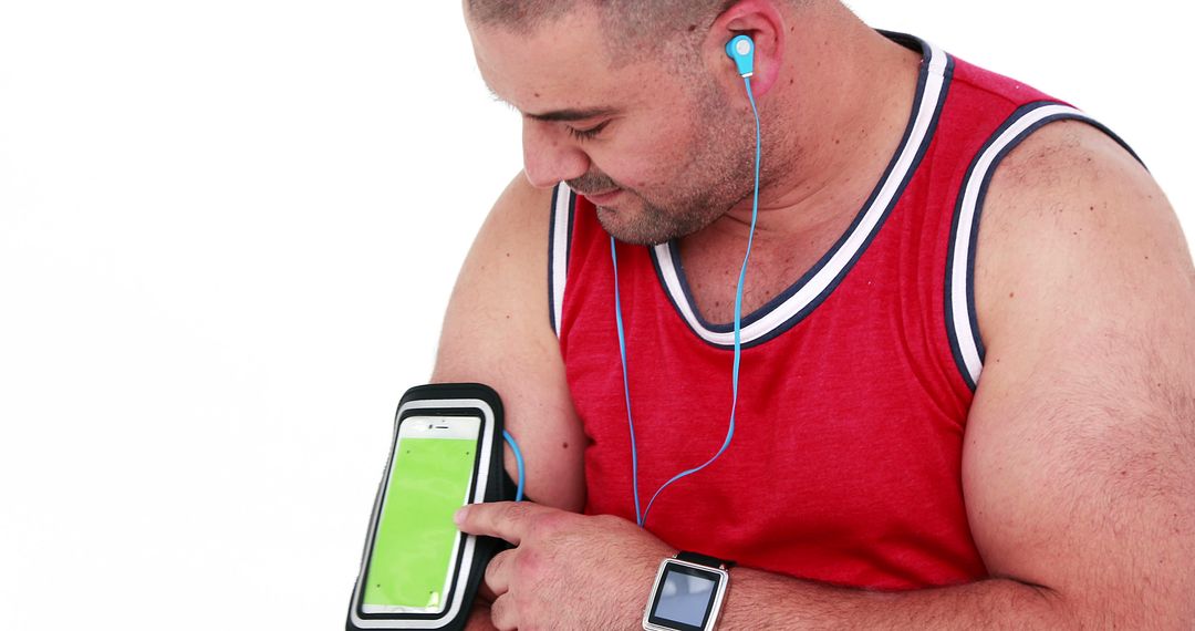 Man Using Smartphone with Arm Band While Listening to Music on Earbuds - Free Images, Stock Photos and Pictures on Pikwizard.com