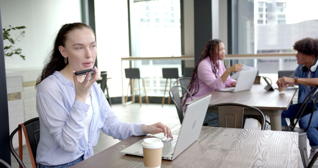 Woman Recording Voice Message While Working on Laptop in Office