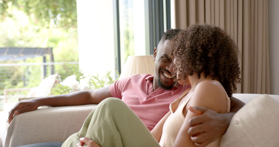 Happy Couple Relaxing on Couch at Home With Big Smiles