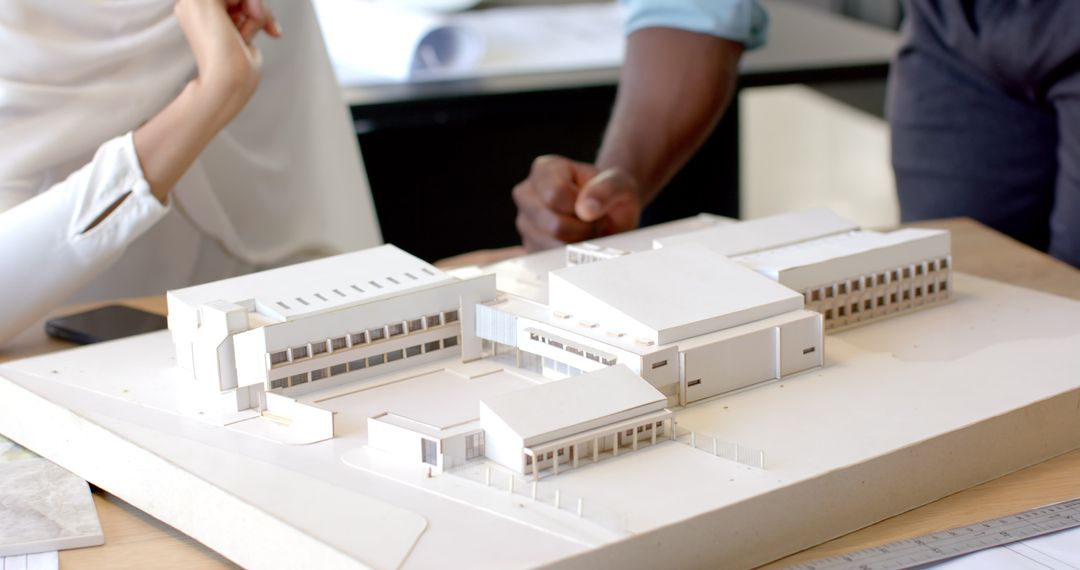 Professionals Discussing Detailed Architectural Model in Office