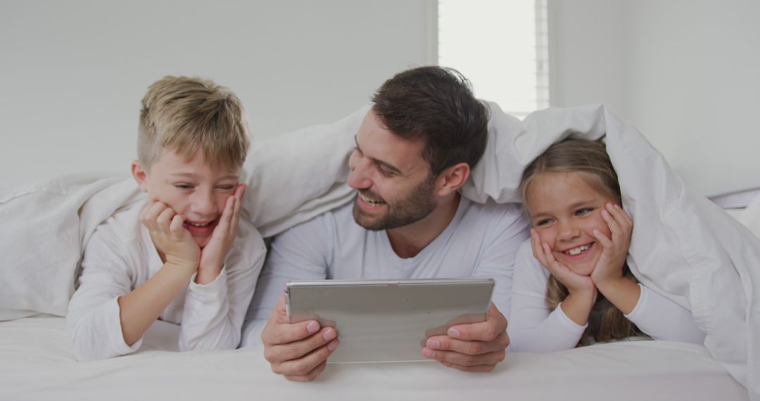 Happy Father With Two Children Using Tablet in Bed - Free Images, Stock Photos and Pictures on Pikwizard.com