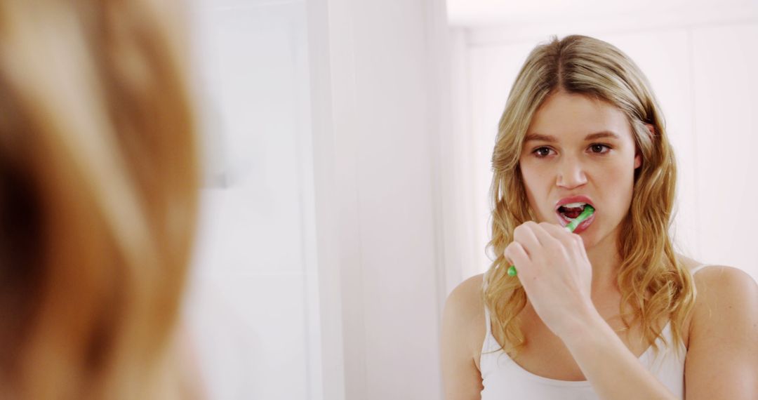 Young woman brushing teeth in bathroom - Free Images, Stock Photos and Pictures on Pikwizard.com