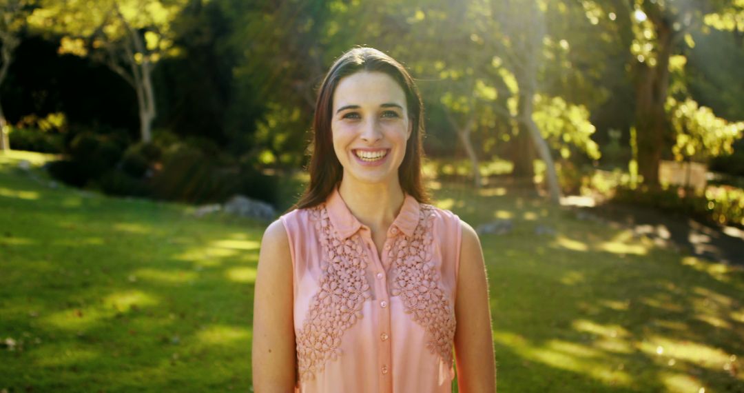 Smiling Woman Standing in Sunlit Park - Free Images, Stock Photos and Pictures on Pikwizard.com