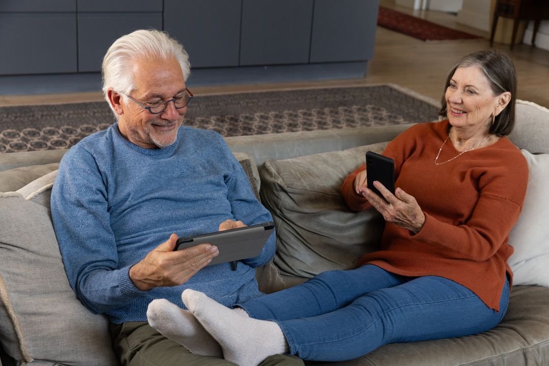 Senior Couple Relaxing on Sofa with Digital Devices