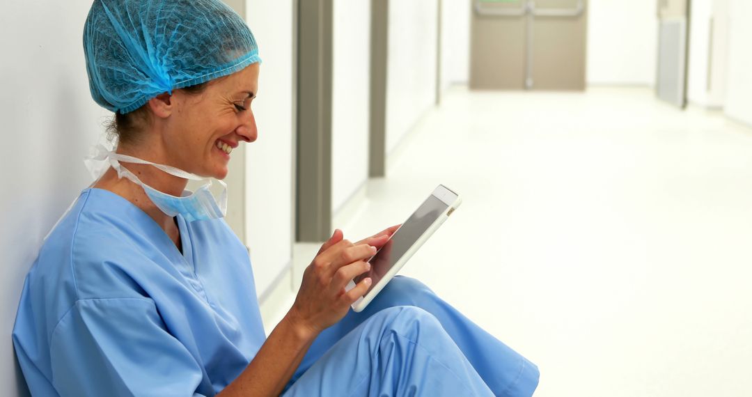 Smiling Nurse in Scrubs Using Digital Tablet in Hospital Hallway - Free Images, Stock Photos and Pictures on Pikwizard.com