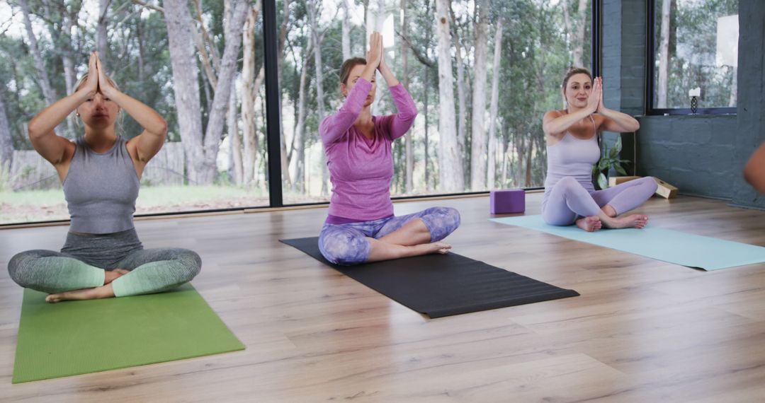 Yoga Practitioners Meditating in Modern Studio with Large Windows - Free Images, Stock Photos and Pictures on Pikwizard.com