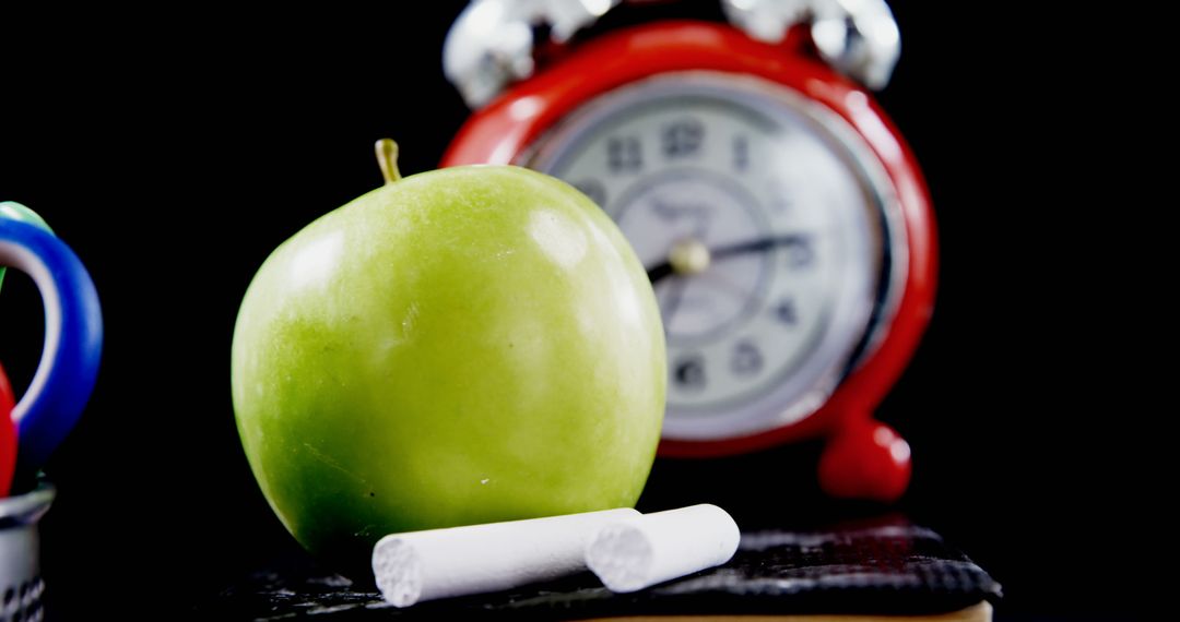 Green Apple with Chalk Sticks and Red Alarm Clock on Black Background - Free Images, Stock Photos and Pictures on Pikwizard.com