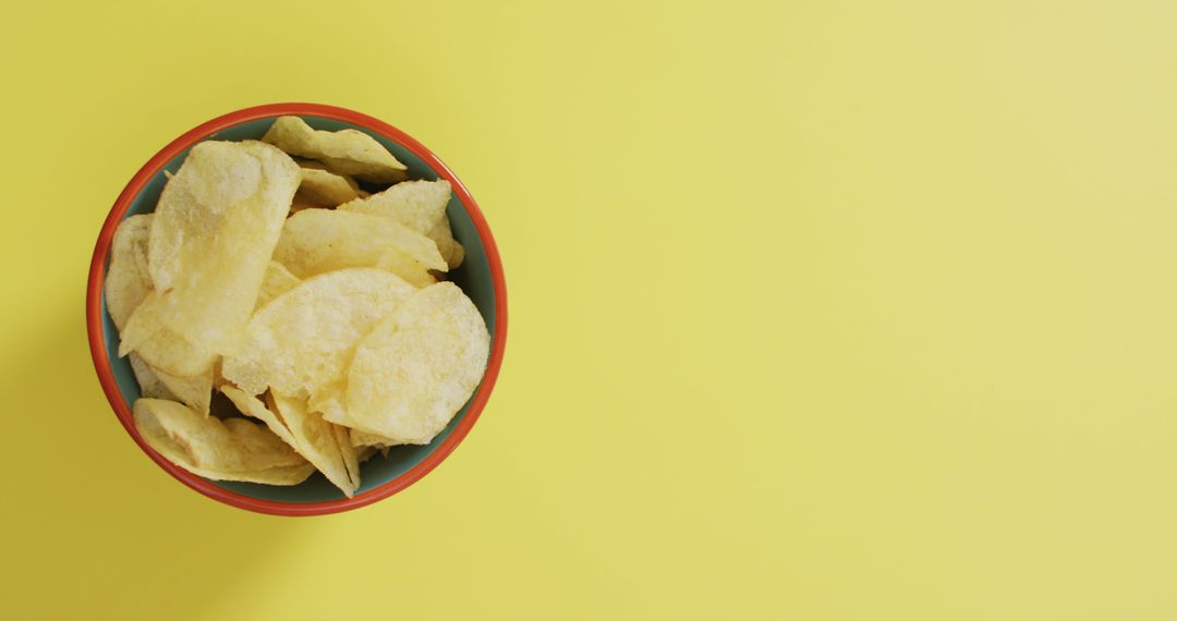Bowl of crisp potato chips on bright yellow background - Free Images, Stock Photos and Pictures on Pikwizard.com